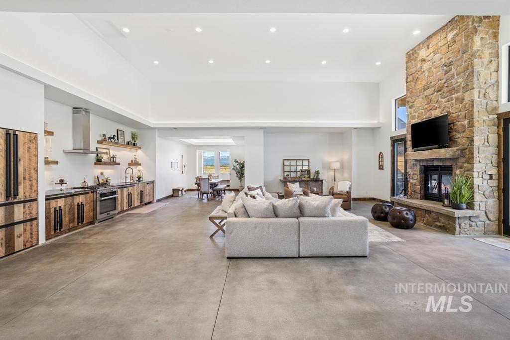 Spacious living area featuring high ceilings, concrete flooring, and a floor-to-ceiling stone fireplace