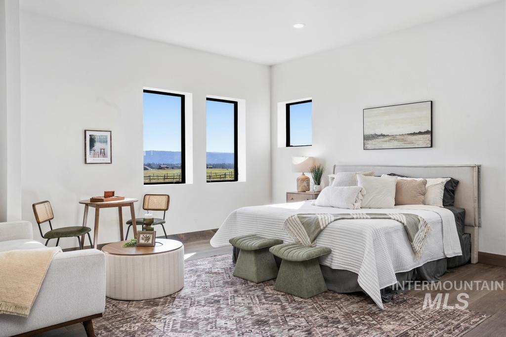 Spacious room featuring multiple large windows, wood-finish flooring, recessed lighting, and a padded headboard