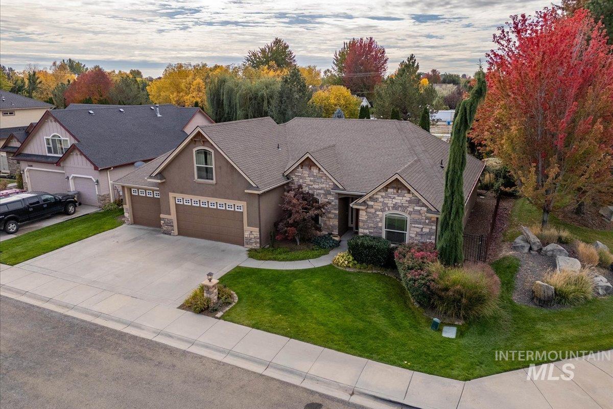 Craftsman-style home featuring stone siding, driveway, a front yard, and a shingled roof