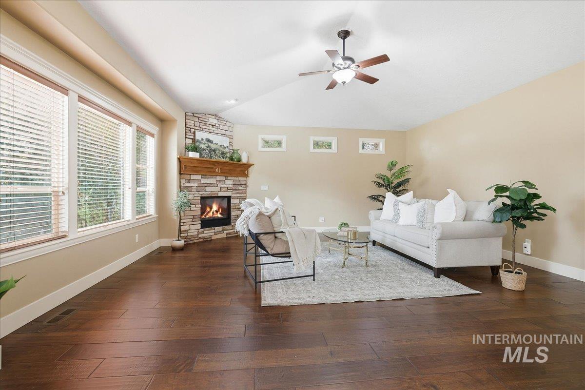 Living area featuring lofted ceiling, dark wood-style flooring, a fireplace, and ceiling fan