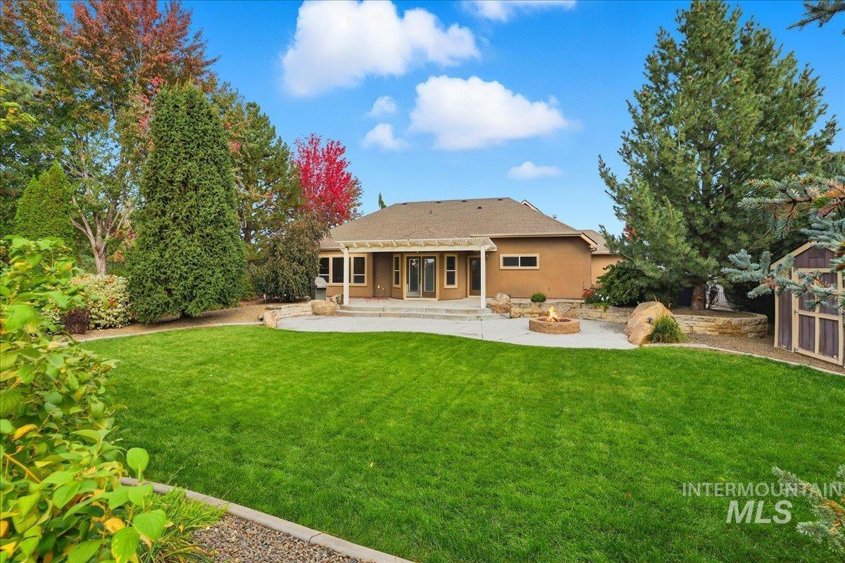 Back of property with a yard, stucco siding, a patio area, and a fire pit