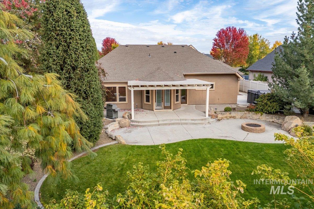 Back of house with a fire pit, a patio area, stucco siding, and a shingled roof
