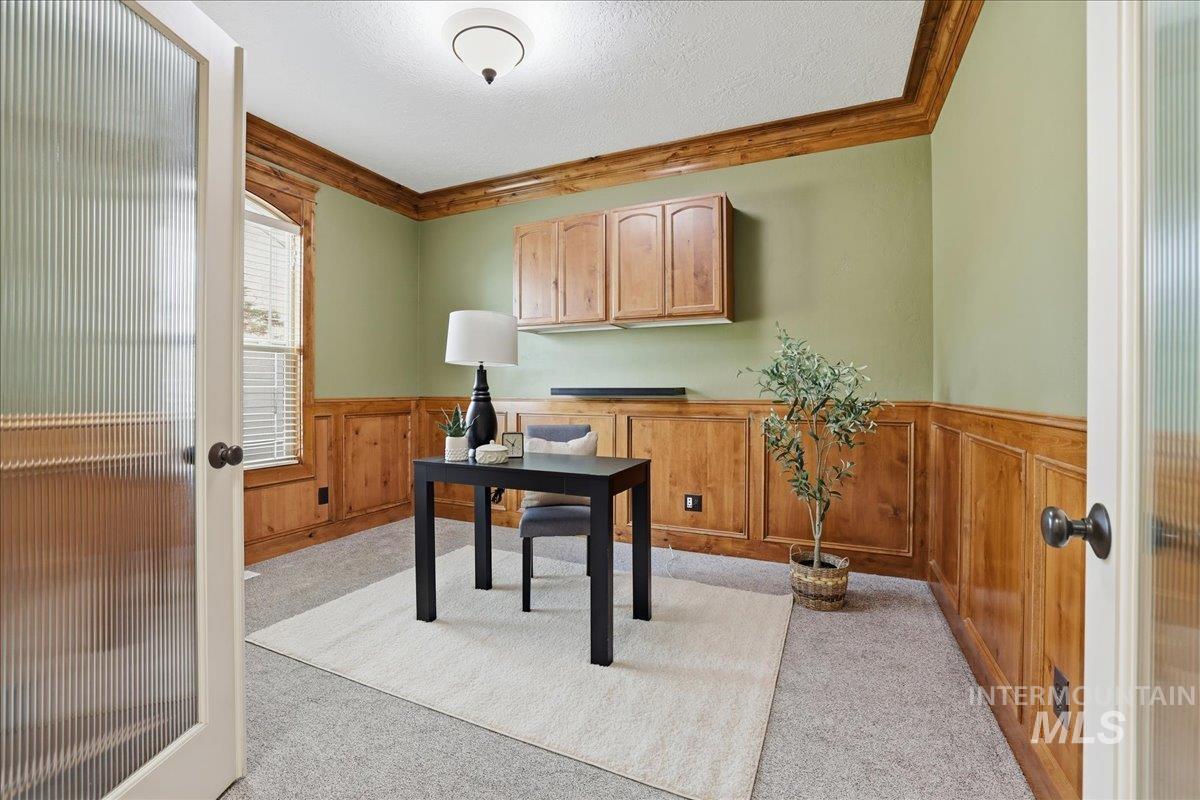 Home office with wainscoting, light colored carpet, french doors, a textured ceiling, and wood walls