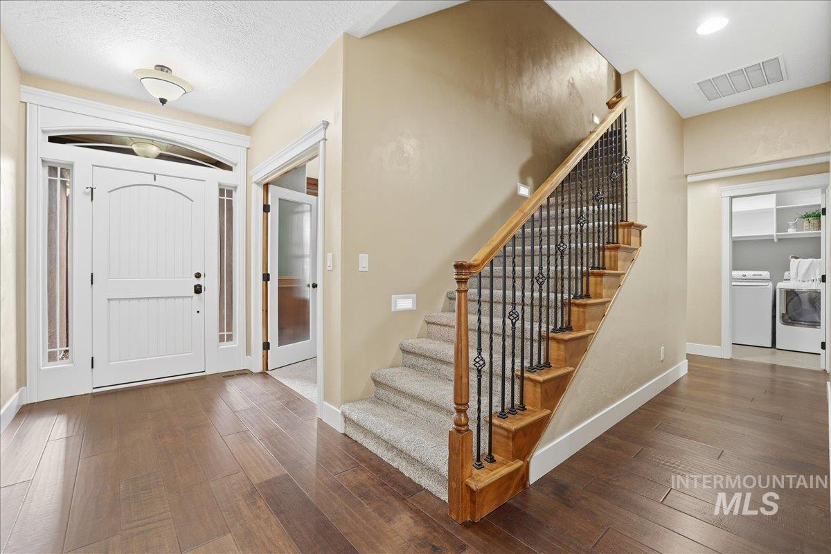 Entrance foyer featuring dark wood-style floors, stairs, washing machine and clothes dryer, and a textured ceiling