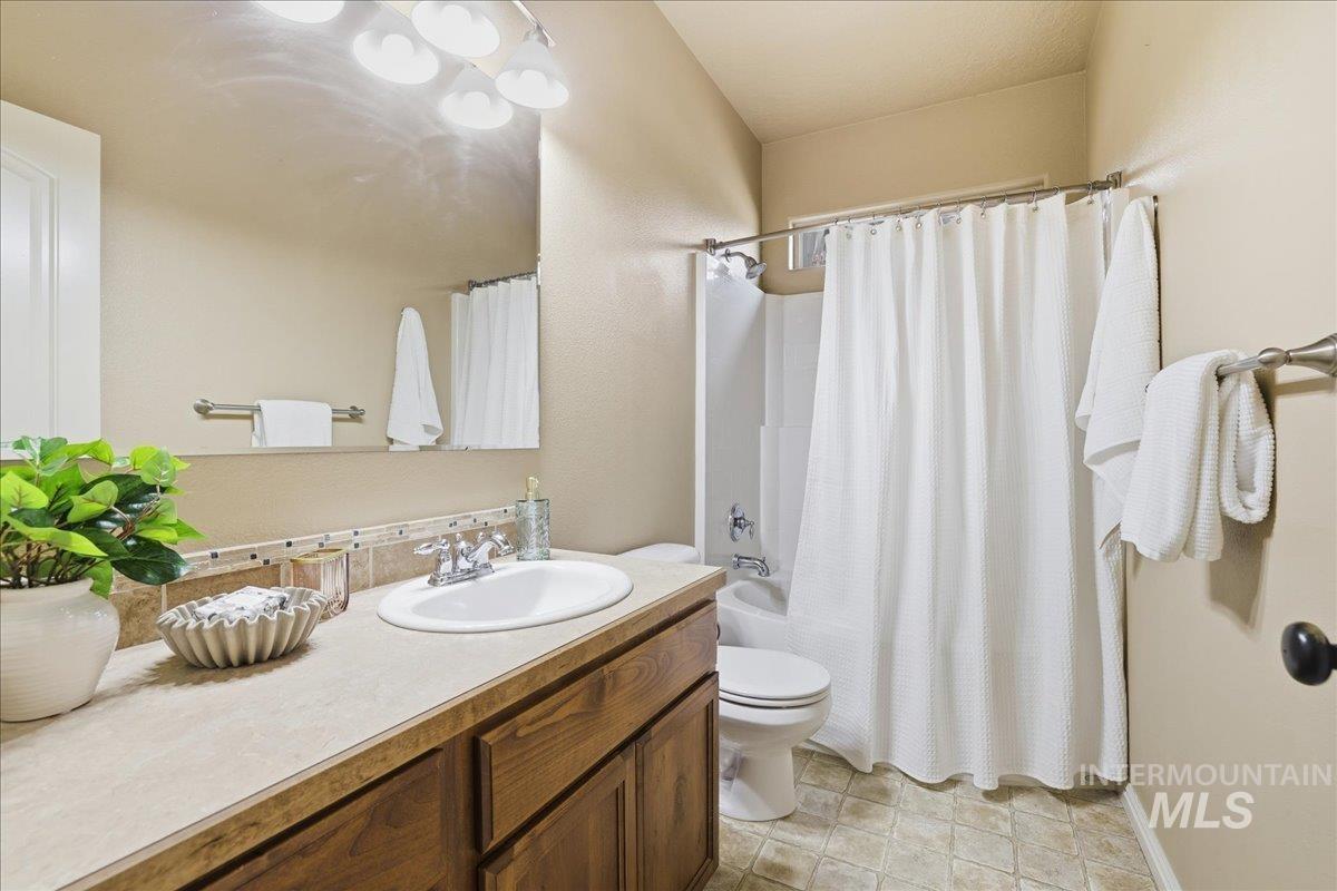 Full bath with shower / tub combo with curtain, vanity, and light tile patterned floors