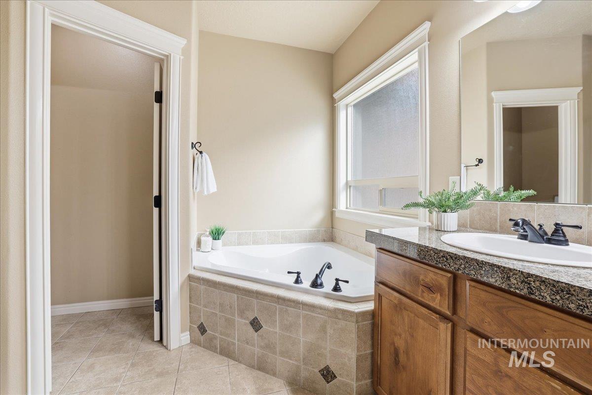 Bathroom featuring a bath, light tile patterned flooring, and vanity