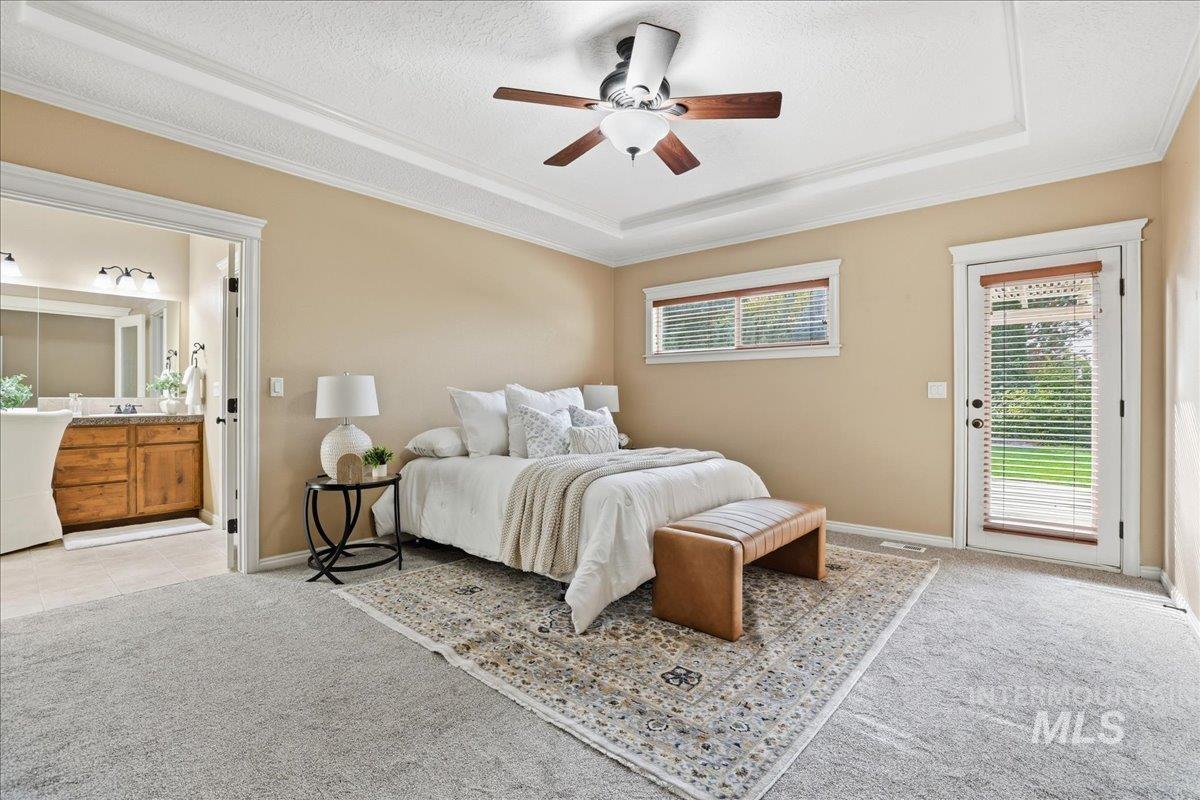 Bedroom with light colored carpet, a raised ceiling, access to exterior, ceiling fan, and a textured ceiling
