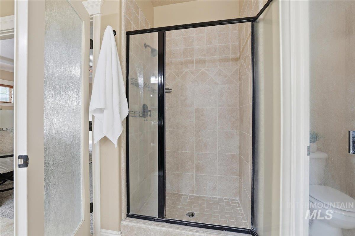 Full bathroom featuring a stall shower and toilet