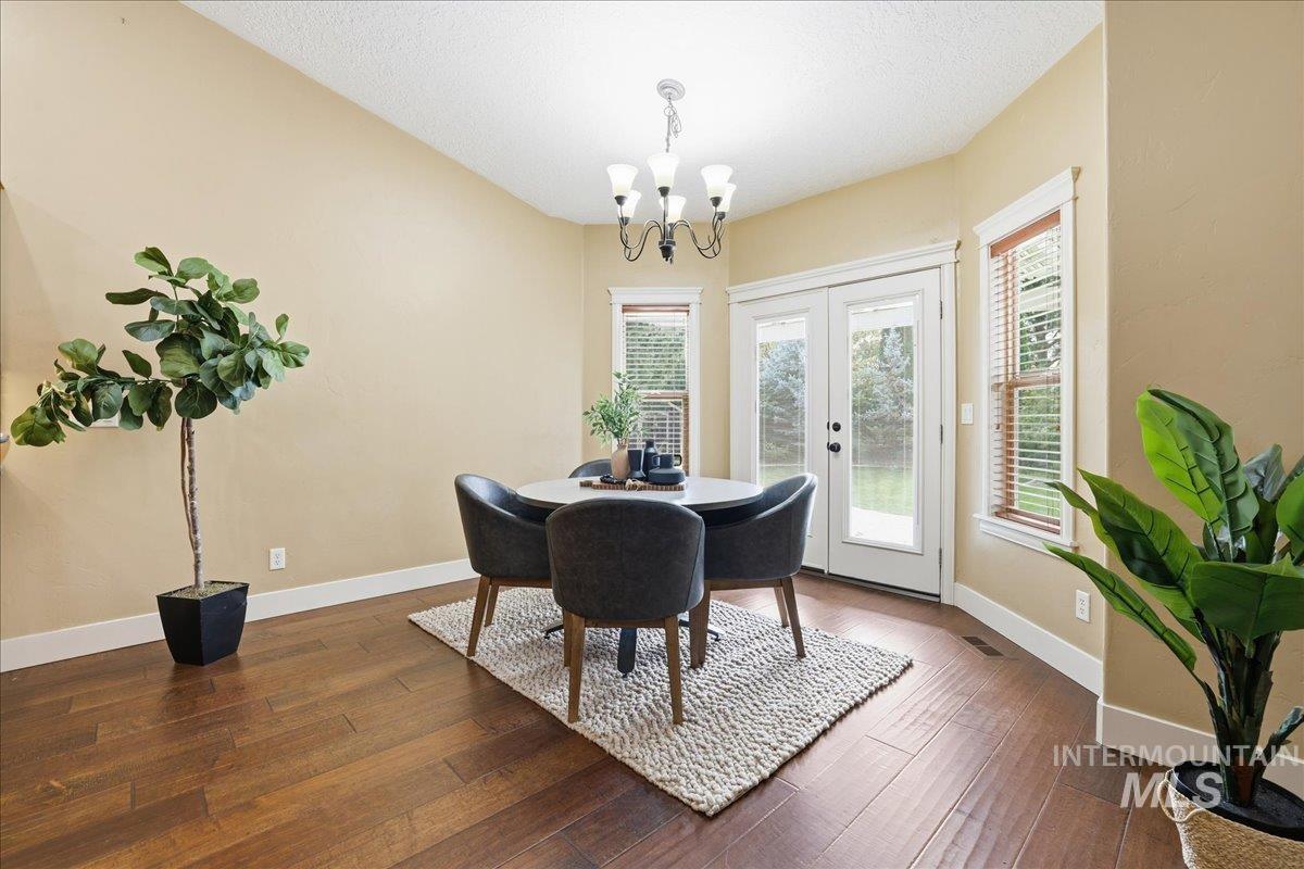 Dining area featuring dark wood finished floors, french doors, a textured ceiling, and a chandelier