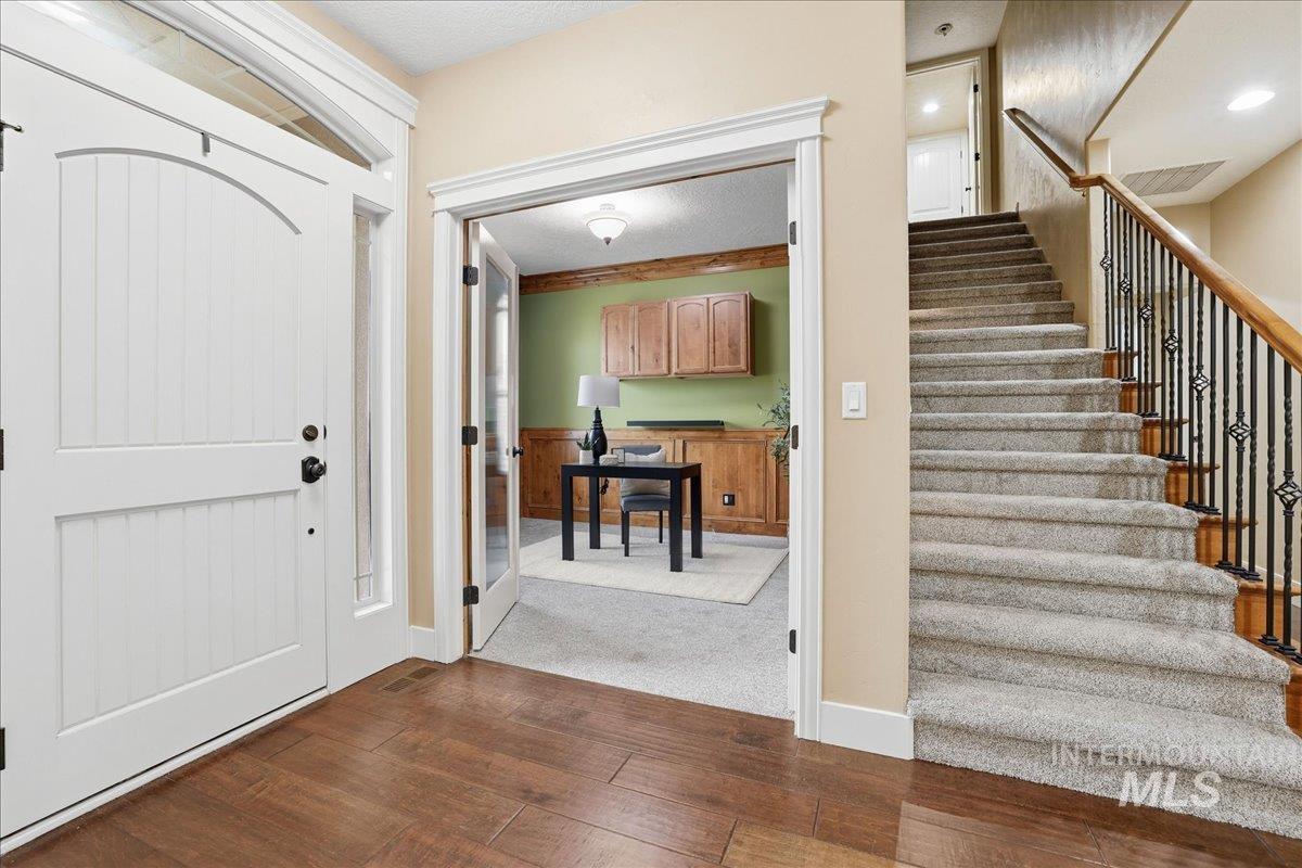Entryway featuring dark wood-type flooring, stairway, a textured ceiling, and dark carpet
