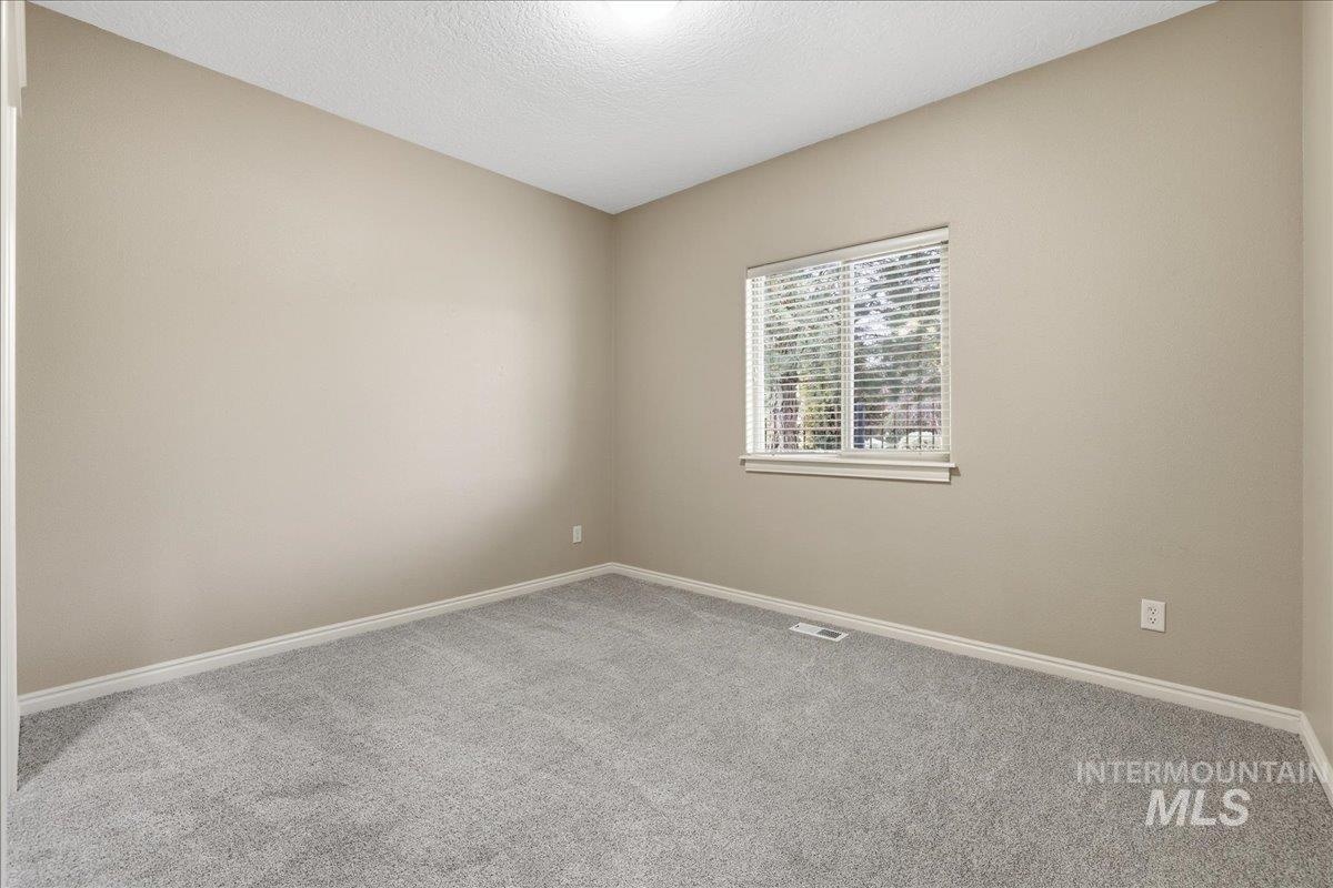 Carpeted empty room with a textured ceiling and baseboards