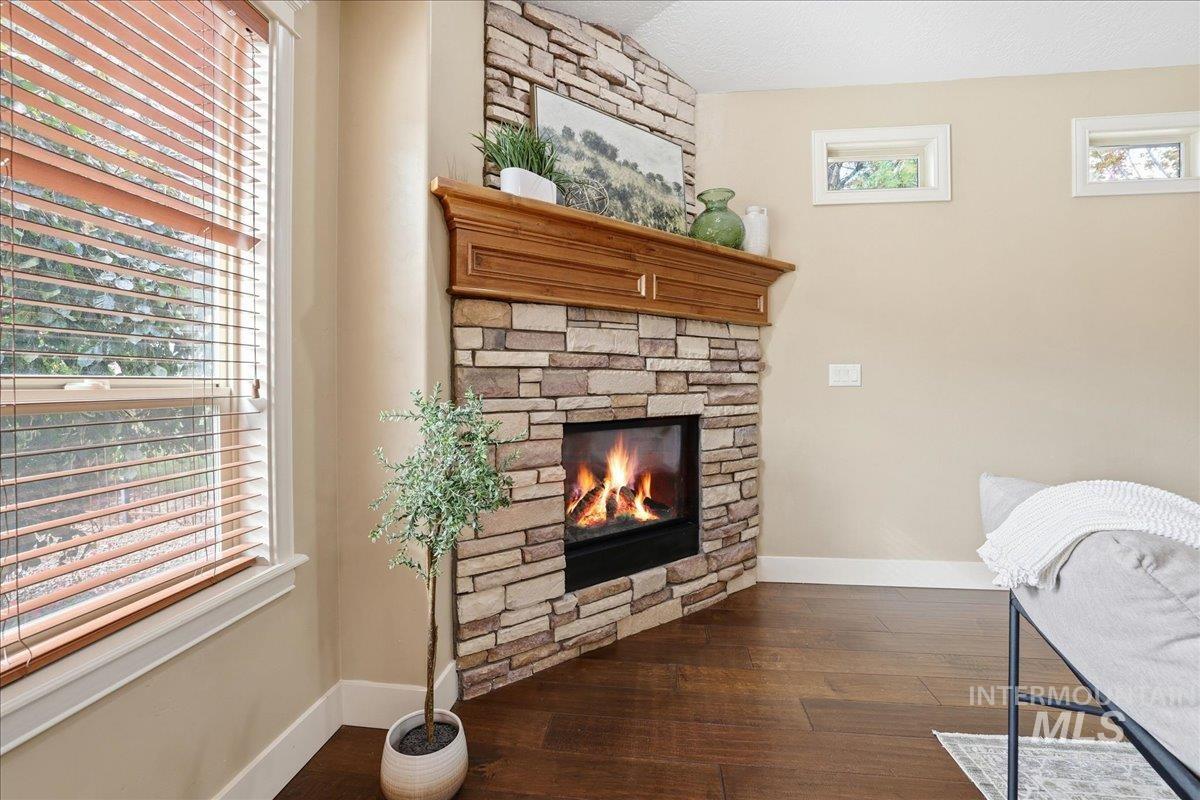 Living area featuring a stone fireplace, dark wood-type flooring, and a textured ceiling