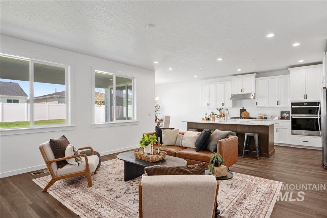 Living area featuring dark wood-style floors, a textured ceiling, and recessed lighting