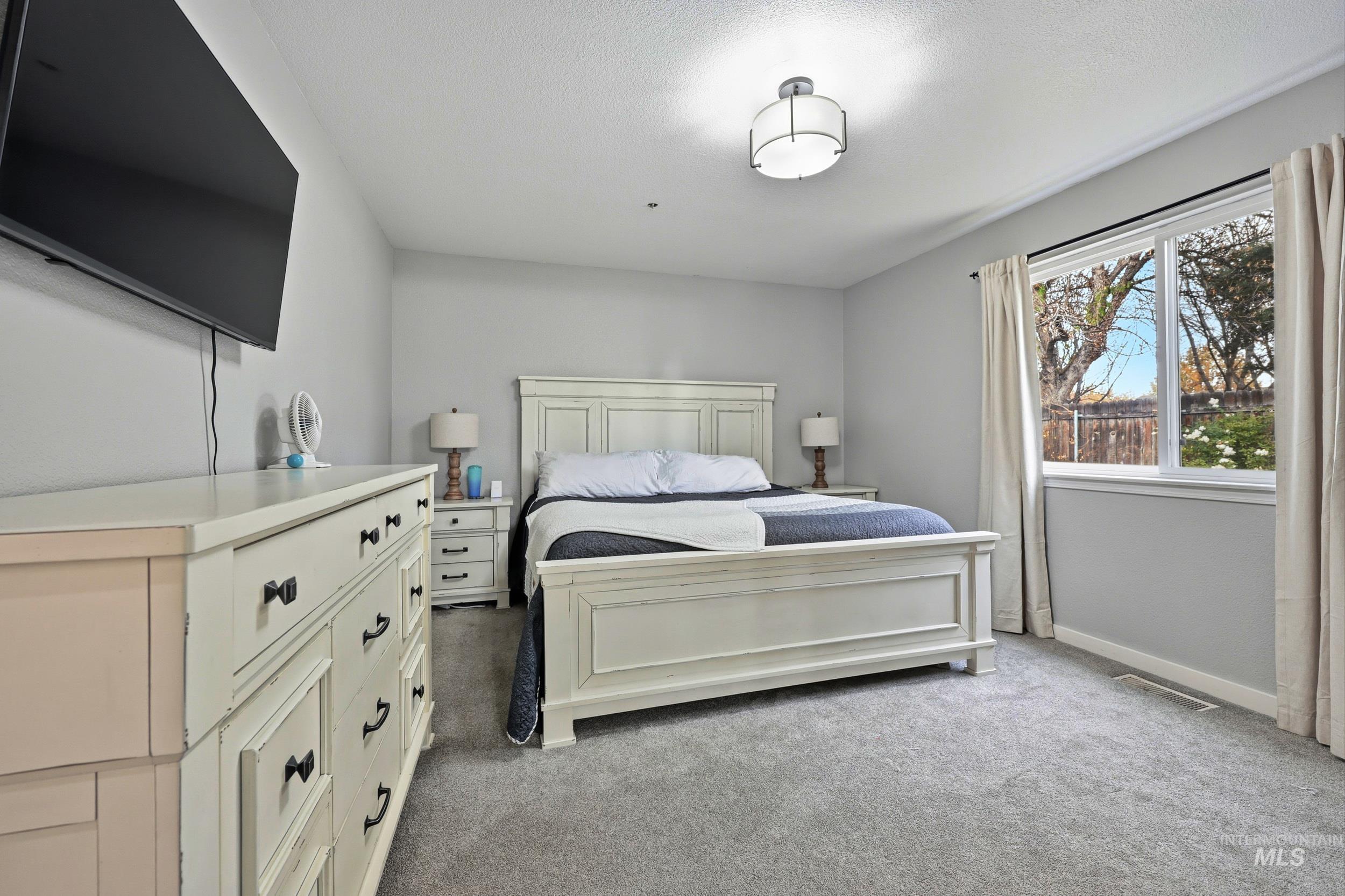 Bedroom featuring light colored carpet and a textured ceiling