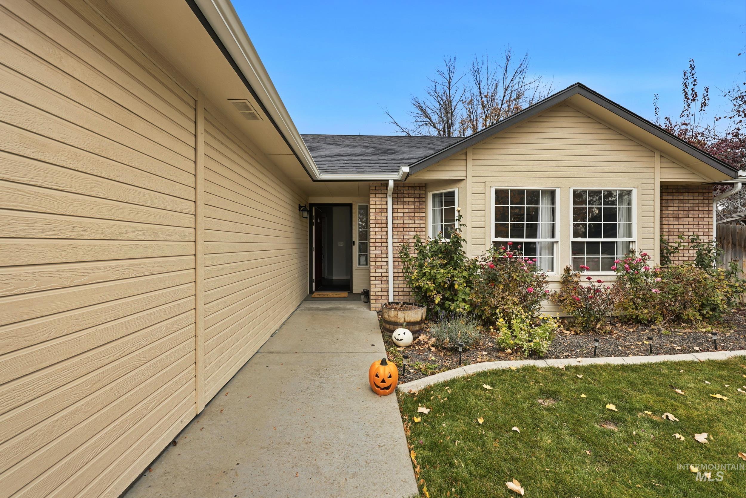 Property entrance with brick siding, a lawn, and roof with shingles