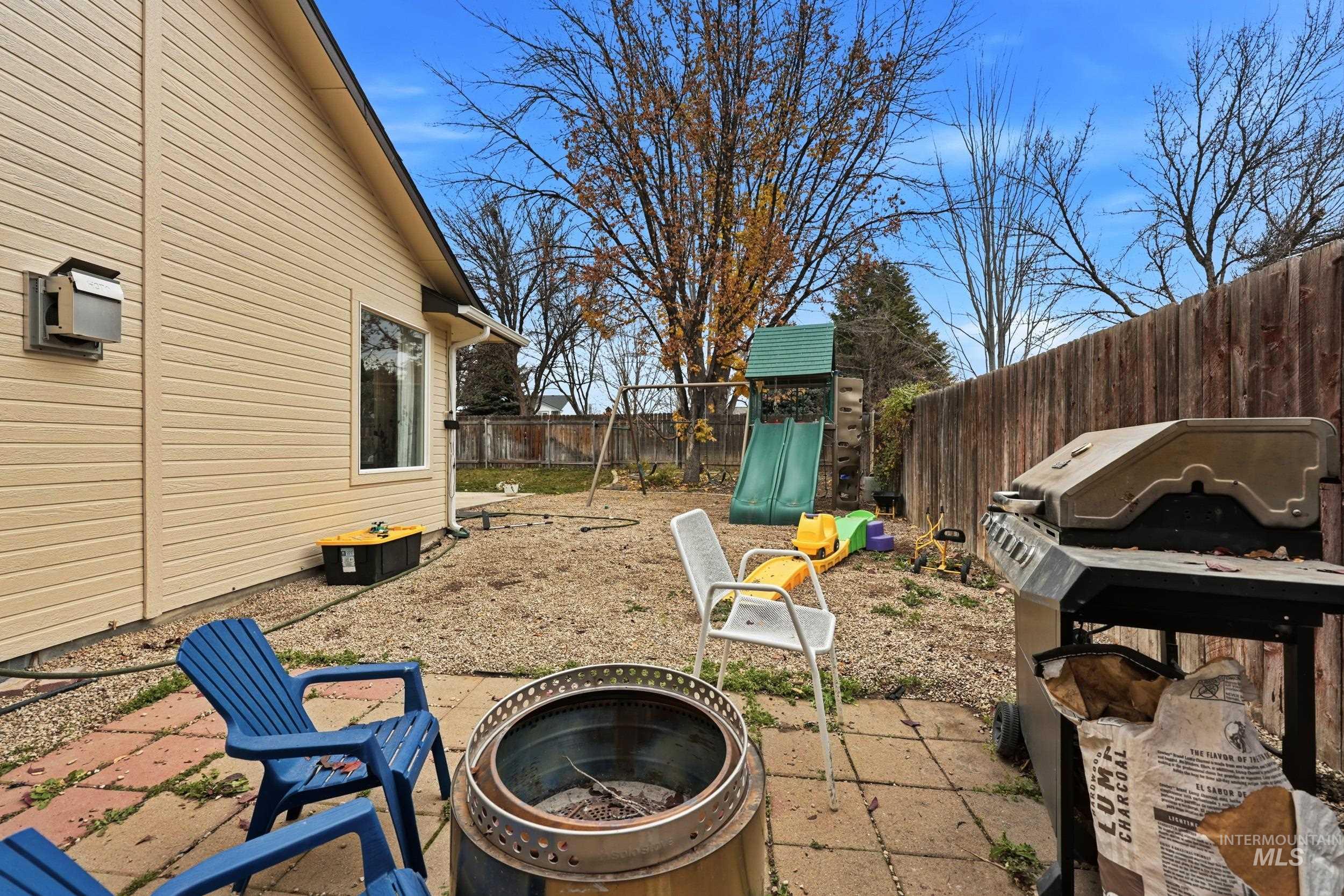 Fenced backyard with a playground, a patio, and area for grilling