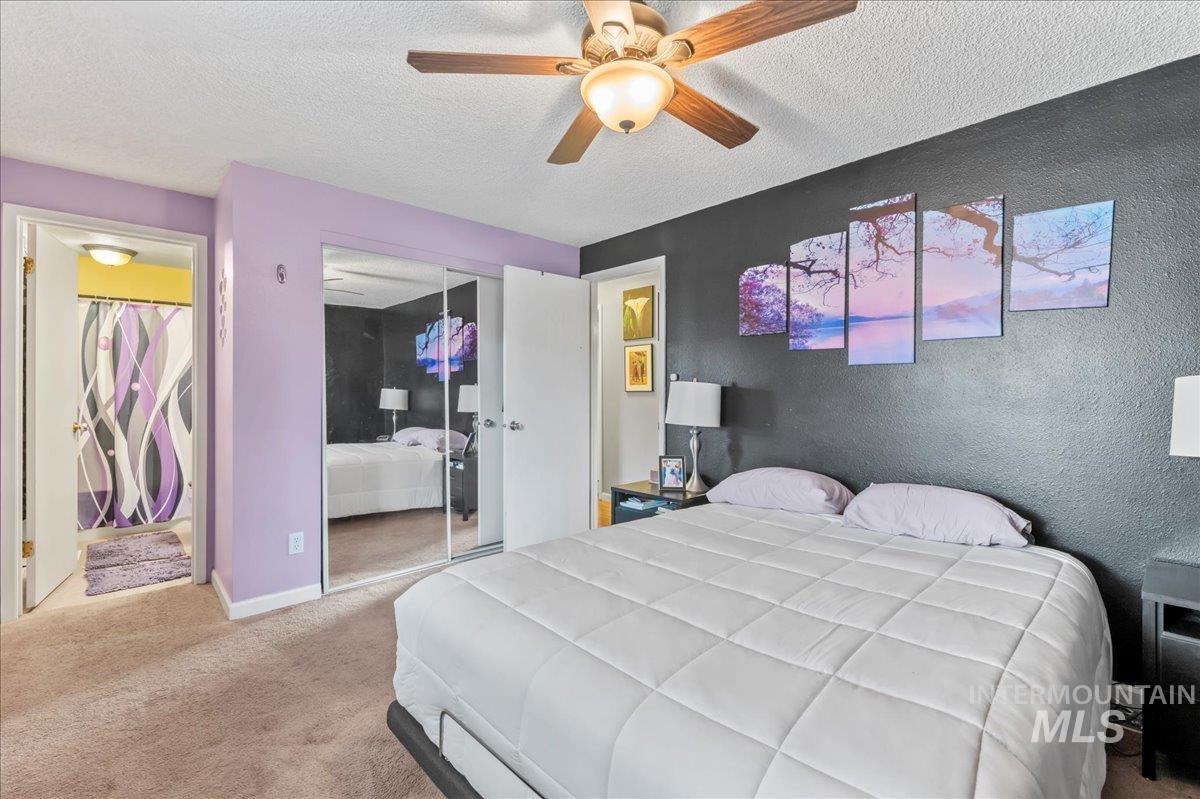 Bedroom featuring carpet, a textured ceiling, a closet, a ceiling fan, and connected bathroom