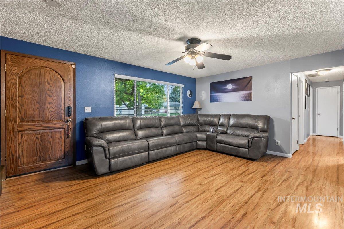 Living room with wood finished floors, a textured ceiling, and a ceiling fan