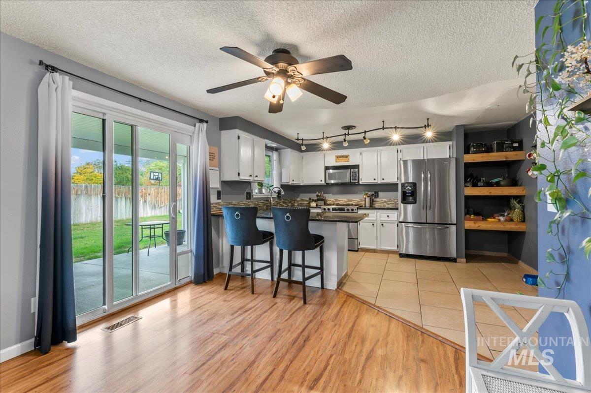 Kitchen with stainless steel appliances, white cabinetry, a textured ceiling, a kitchen bar, and a peninsula