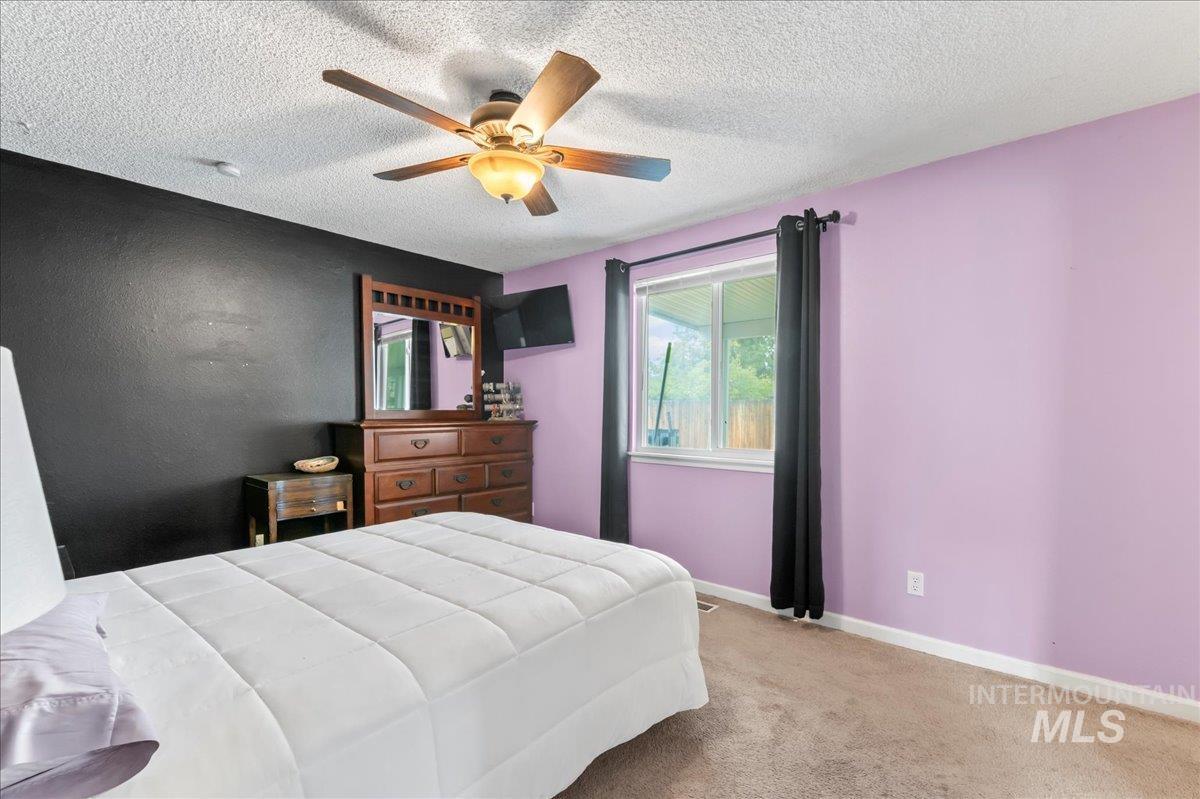 Bedroom with carpet flooring, a textured ceiling, and ceiling fan