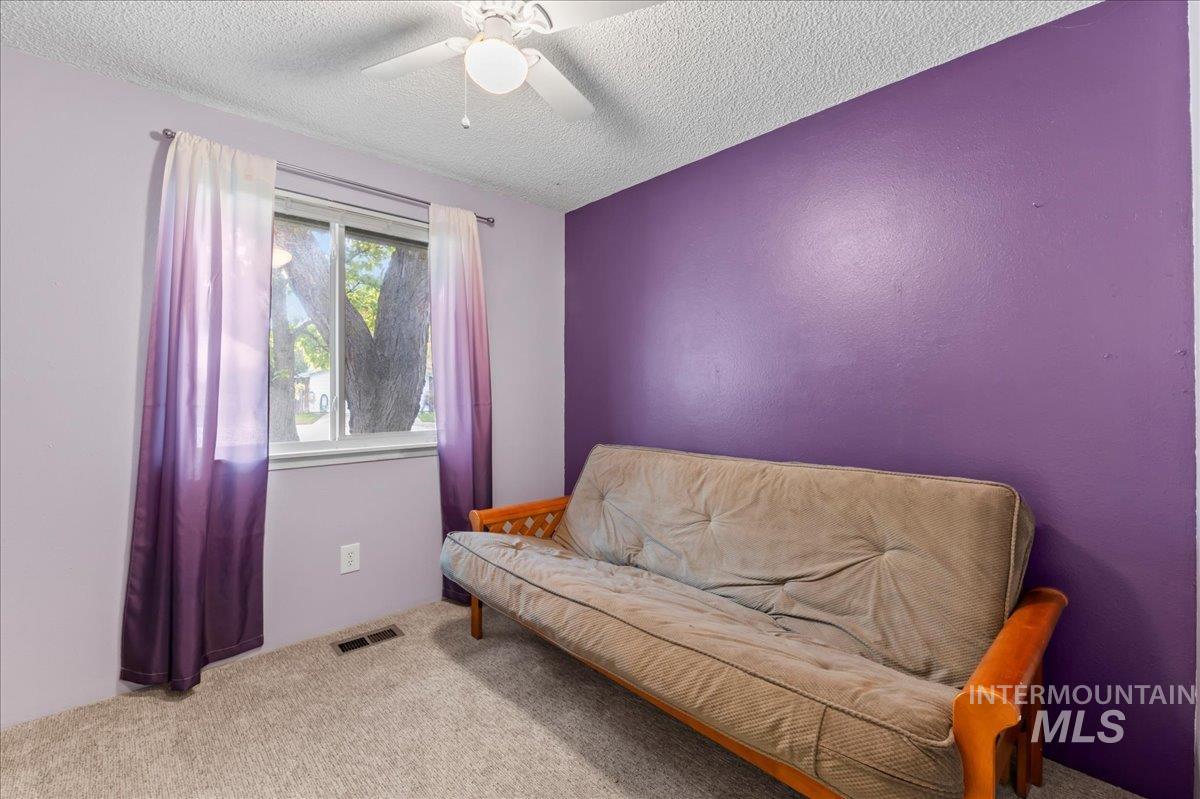 Living area featuring carpet, a textured ceiling, and a ceiling fan