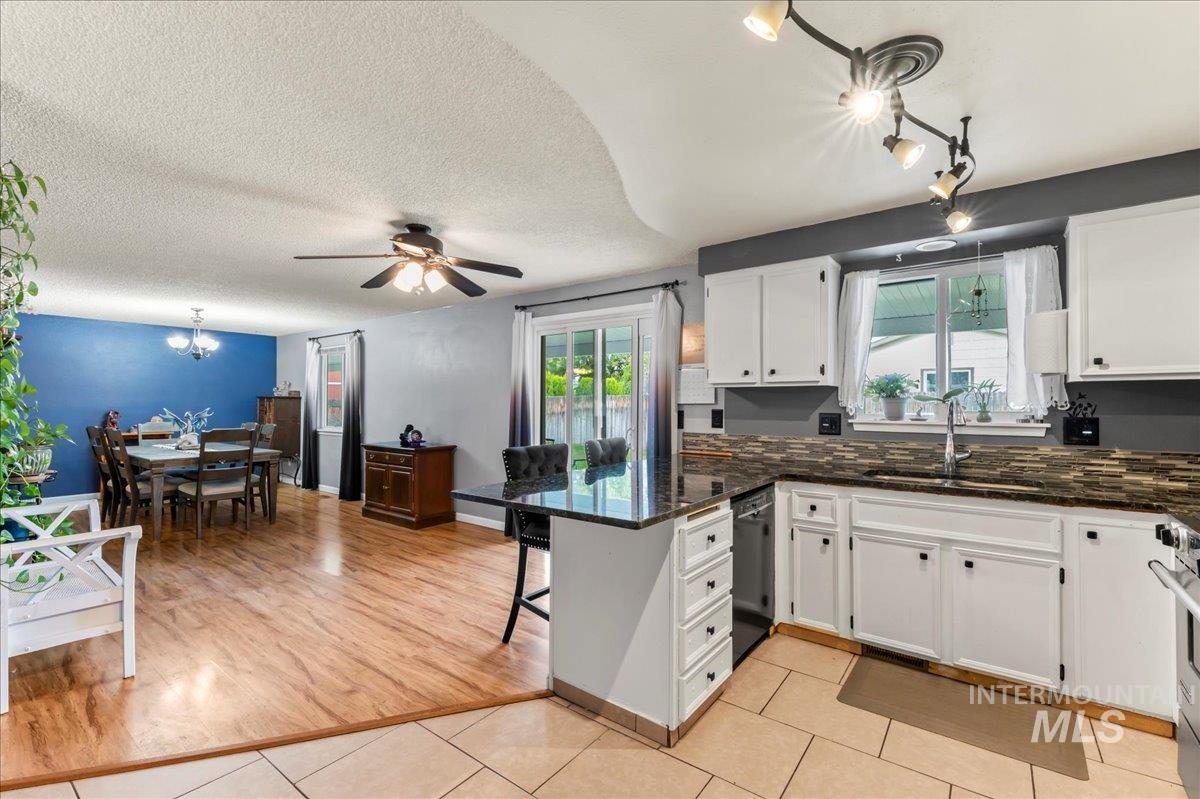 Kitchen featuring a peninsula, hanging light fixtures, white cabinetry, a breakfast bar area, and dark stone counters