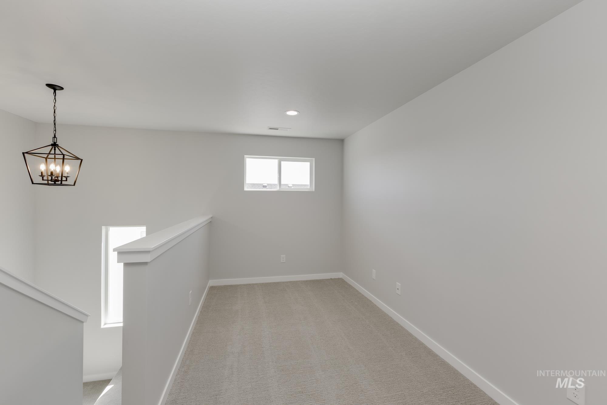 Empty room featuring a chandelier, light carpet, and recessed lighting
