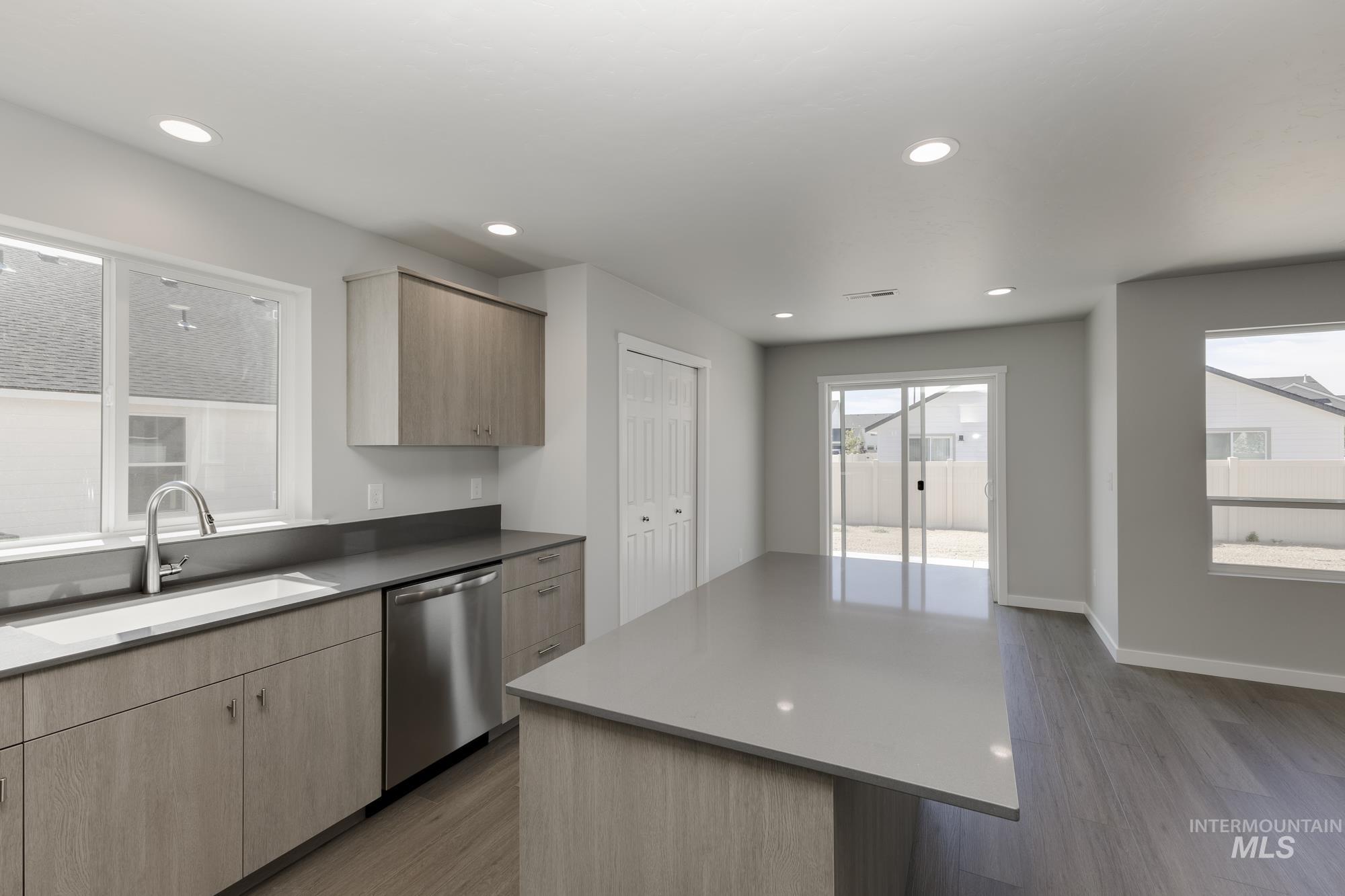 Kitchen featuring stainless steel dishwasher, wood finished floors, light brown cabinets, modern cabinets, and recessed lighting