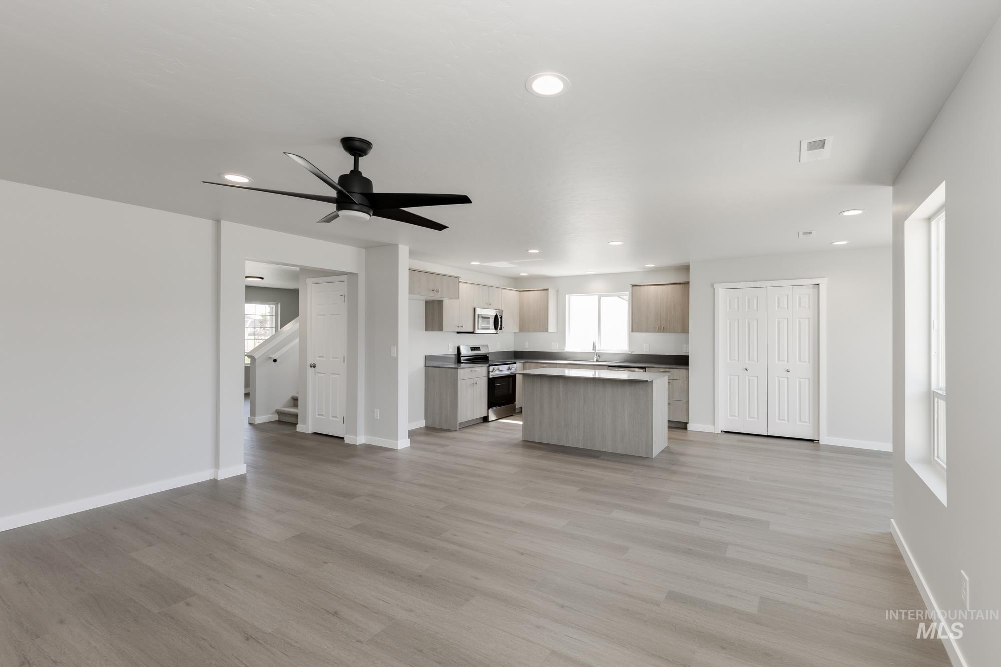 Kitchen featuring appliances with stainless steel finishes, open floor plan, light wood-type flooring, ceiling fan, and recessed lighting