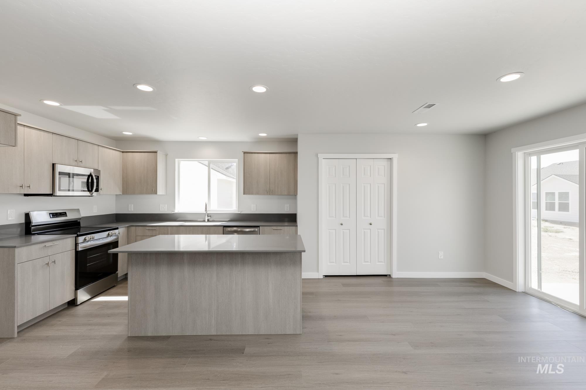 Kitchen with appliances with stainless steel finishes, light brown cabinets, modern cabinets, light wood-style floors, and recessed lighting