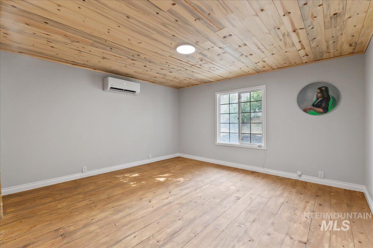 Bedroom 2 with hardwood flooring, wood ceiling, and an heating/AC mini split wall unit.  This room has barn sliding doors for the closet.