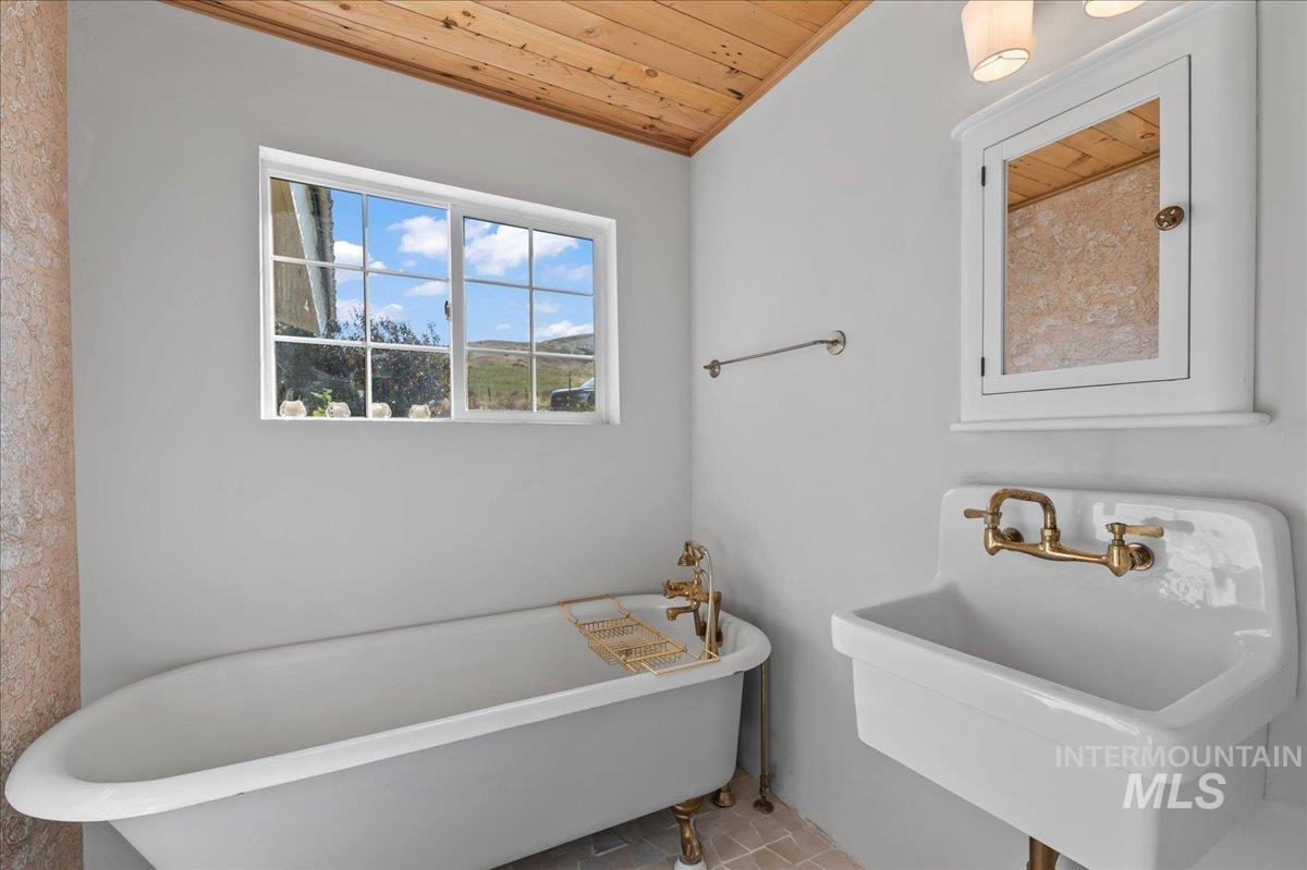 Full bath with wooden ceiling and a claw foot soaking tub/shower