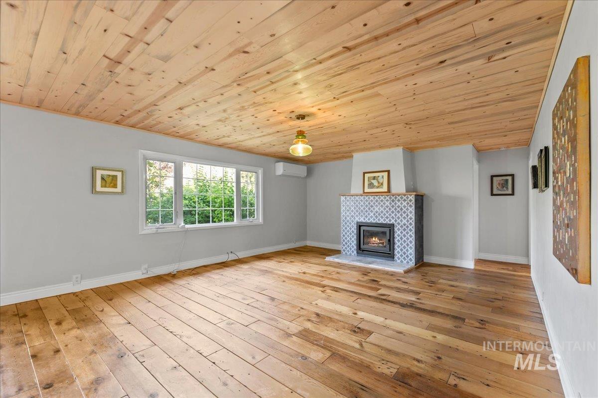Unfurnished living room with wooden ceiling, wood-type flooring, a fireplace, and a wall mounted air conditioner
