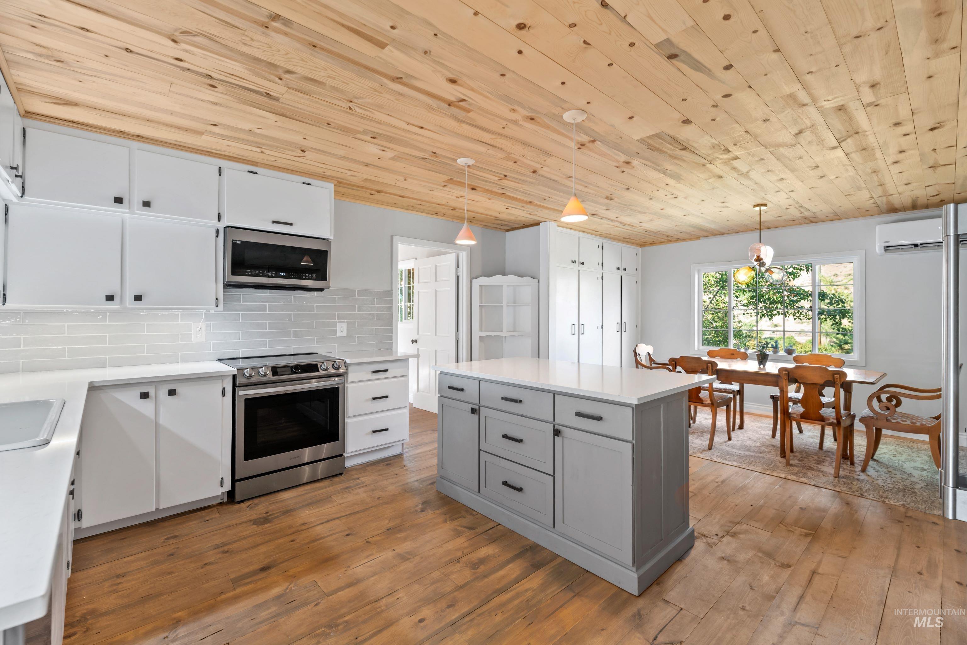 Kitchen featuring stainless steel appliances, wooden ceiling, hardwood floors, quartz countertops, and tile backsplash