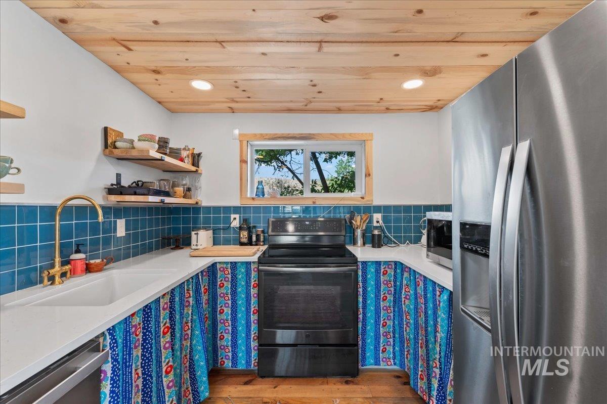 ADU kitchen featuring wood ceiling, appliances with stainless steel finishes, hardwood floors, light quartz countertops, and open shelves