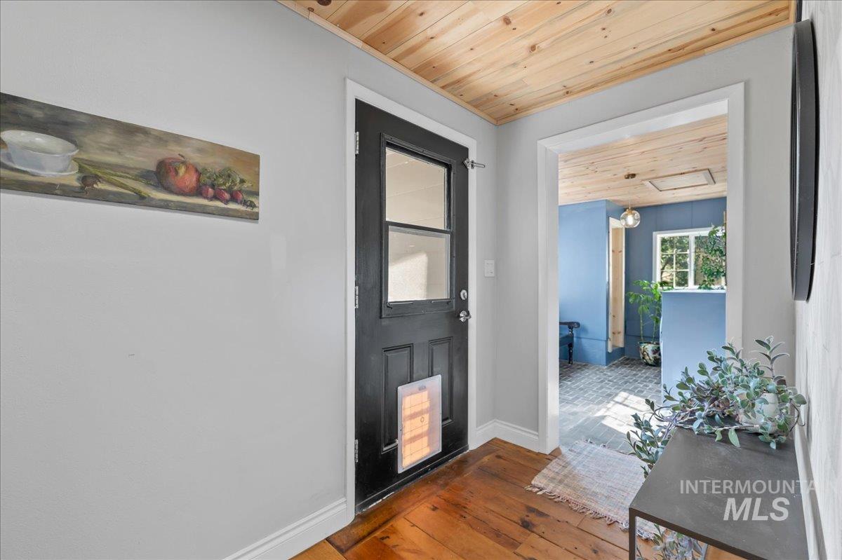 Entryway featuring wood ceiling and wood-type flooring.  This is the main entrance at the back door that leads into the mudroom/kitchen or down the hall to the living room, bathroom and bedrooms
