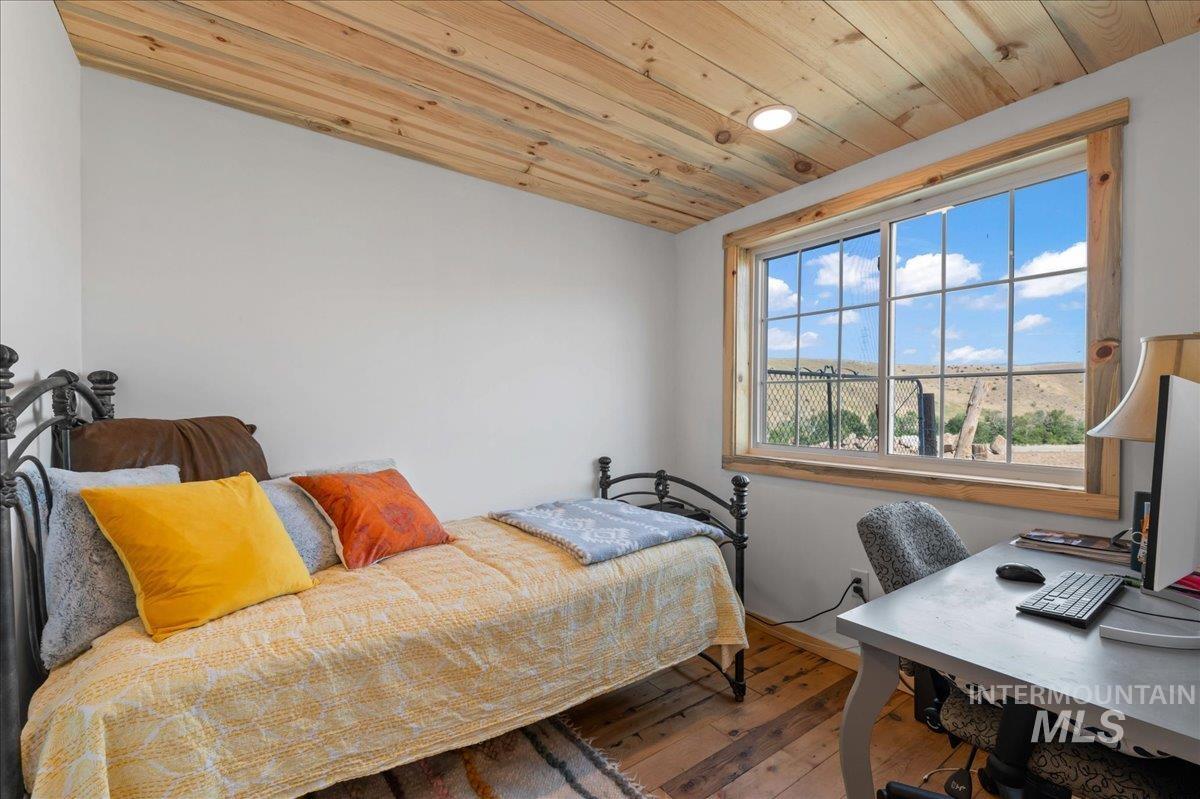 ADU bedroom with hardwood floors, wood ceiling, and a desk.  Perfect for a small bedroom or office area.