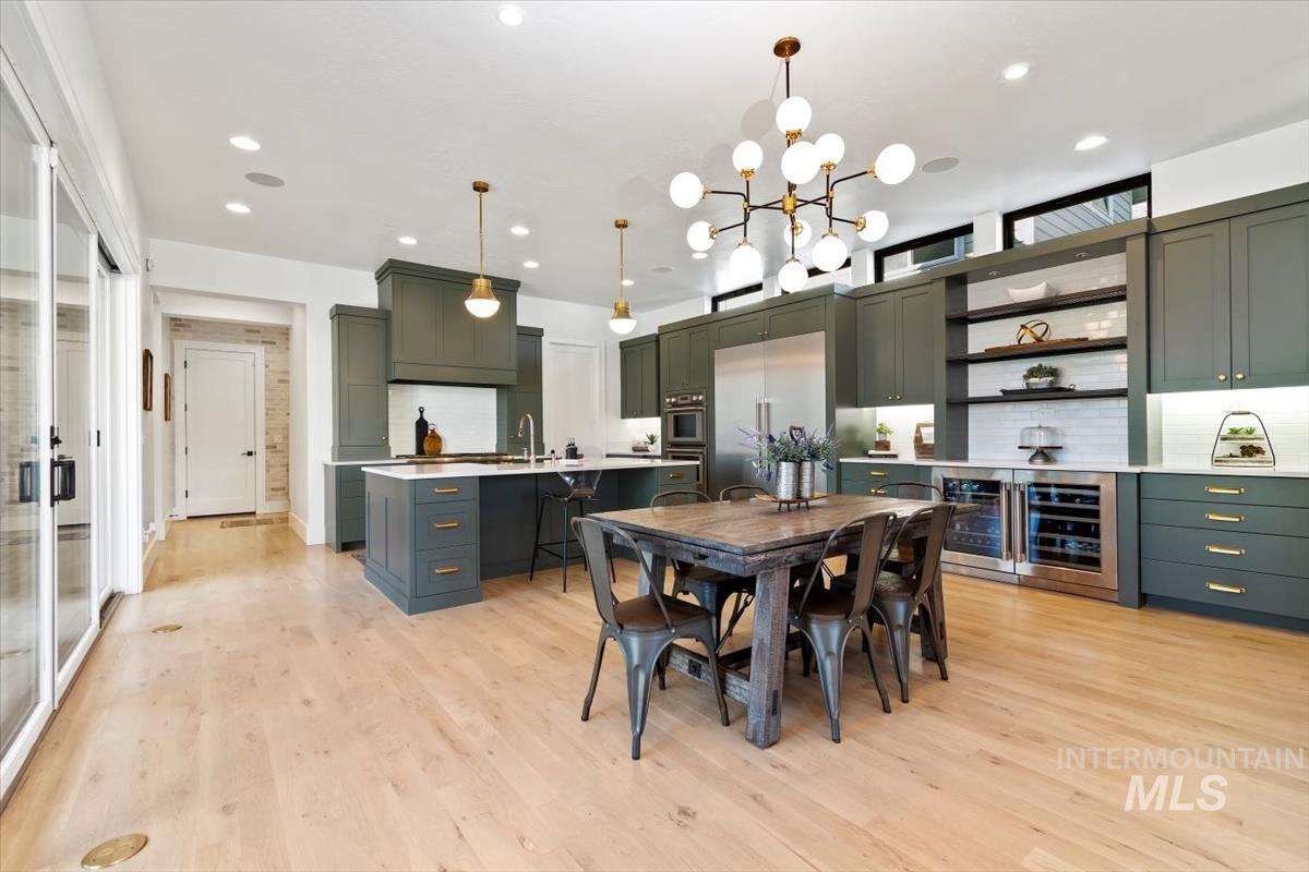 Dining room featuring beverage cooler, light wood-type flooring, recessed lighting, and a chandelier