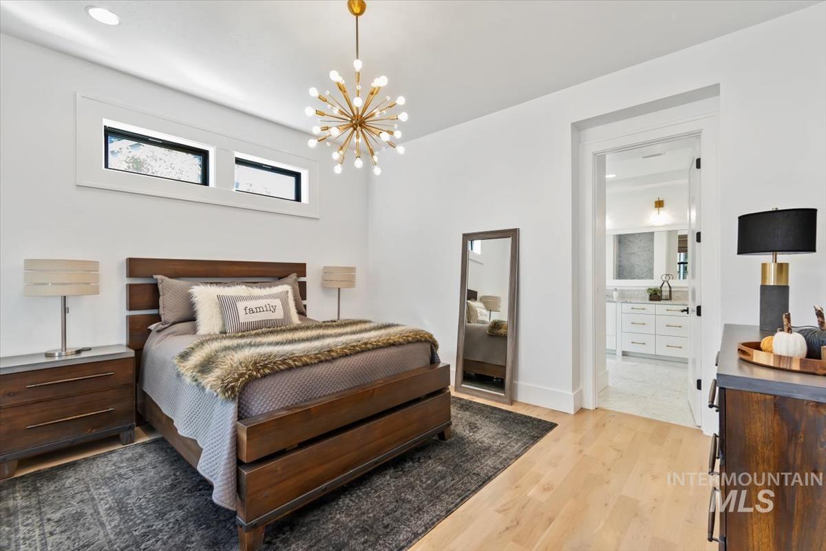 Bedroom featuring light wood finished floors, a chandelier, and ensuite bathroom
