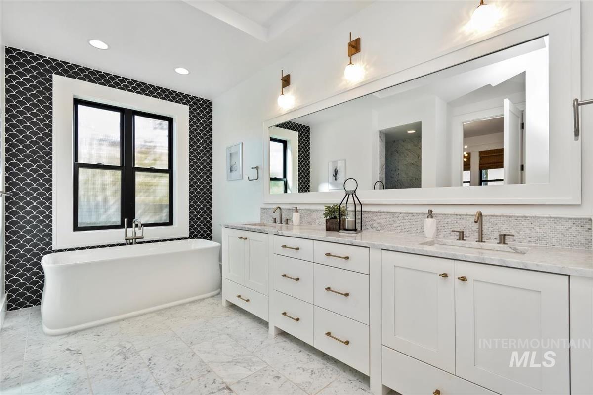 Bathroom featuring double vanity, a freestanding tub, and recessed lighting