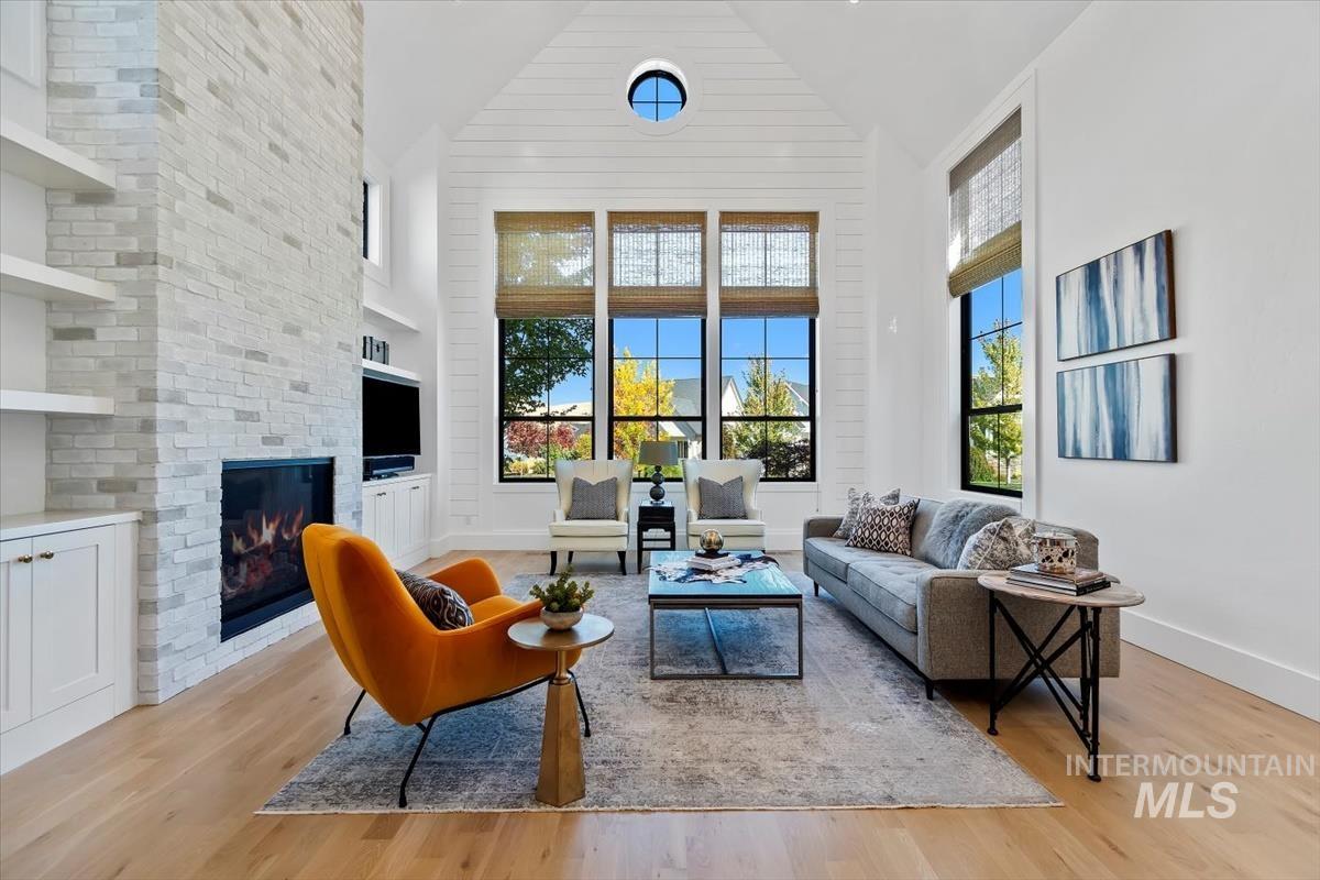 Living room with high vaulted ceiling, a fireplace, and light wood-type flooring