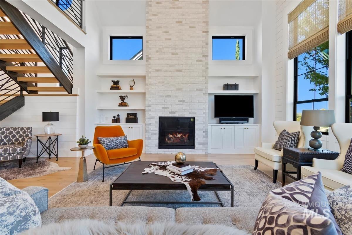Living area with a high ceiling, built in features, wood finished floors, and a fireplace