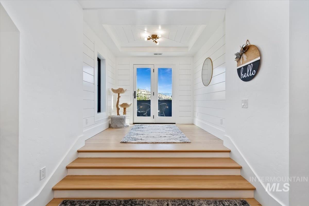 Doorway to outside with a raised ceiling, wood finished floors, and french doors