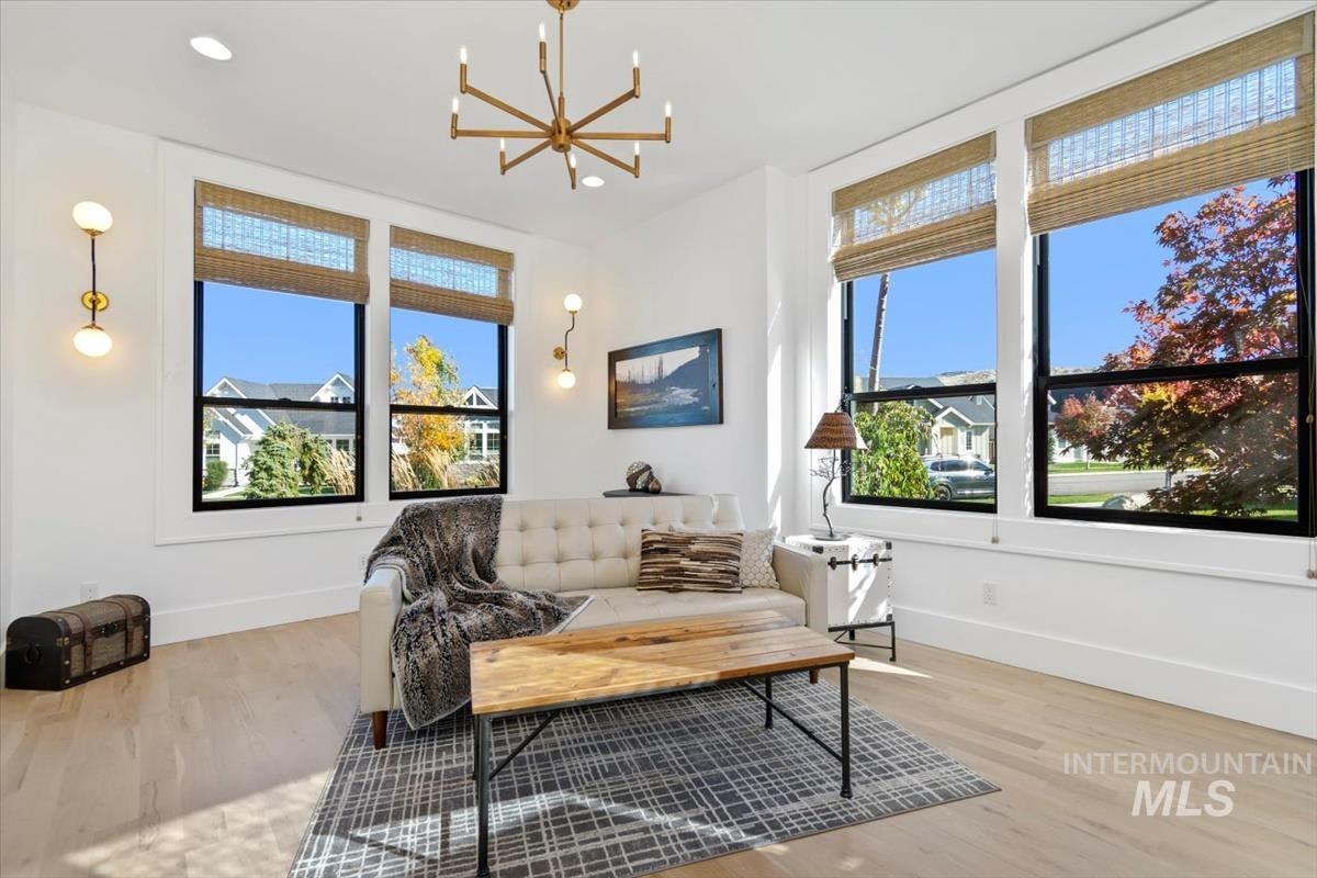 Living area featuring light wood-style floors, healthy amount of natural light, a chandelier, and recessed lighting