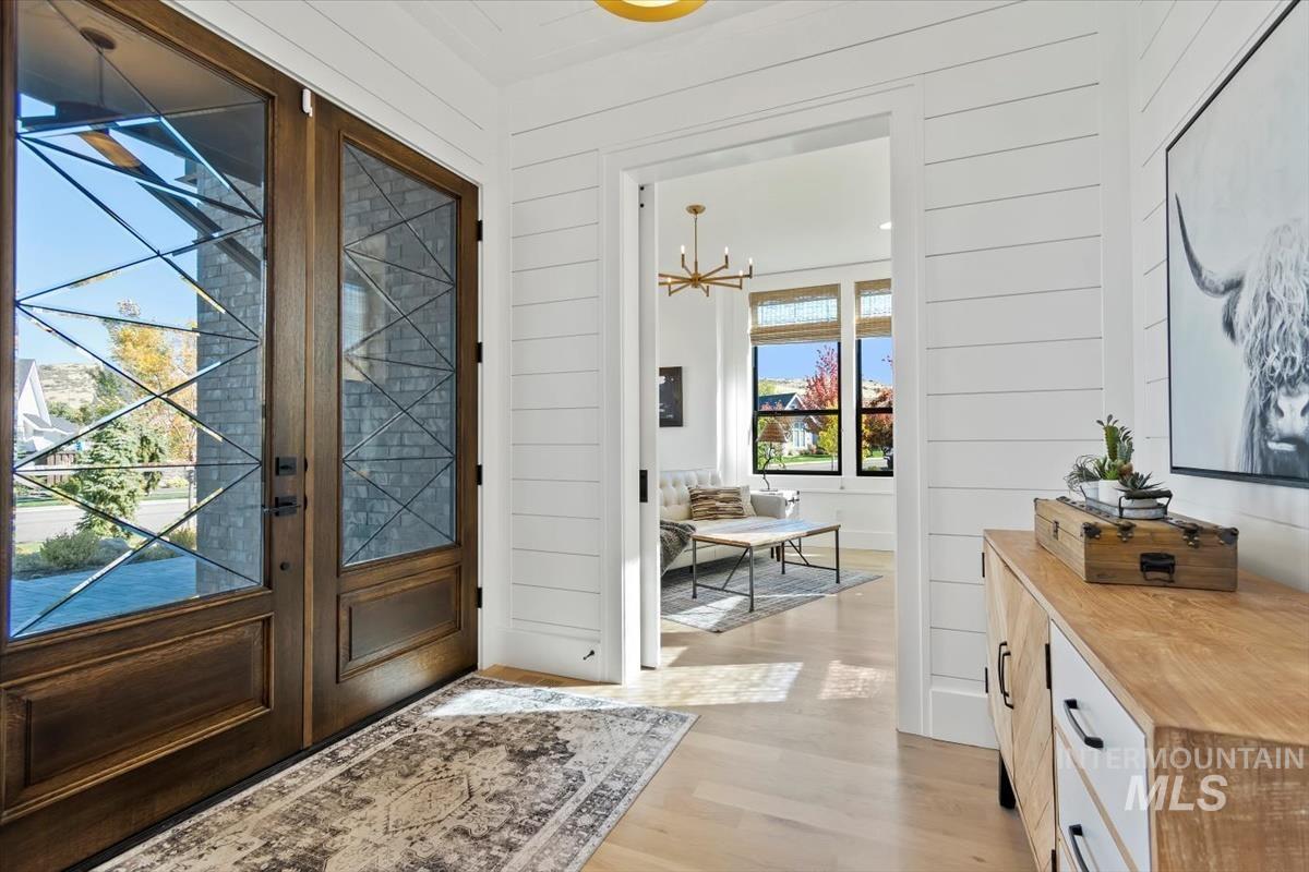 Doorway featuring wood finished floors, wooden walls, and a chandelier