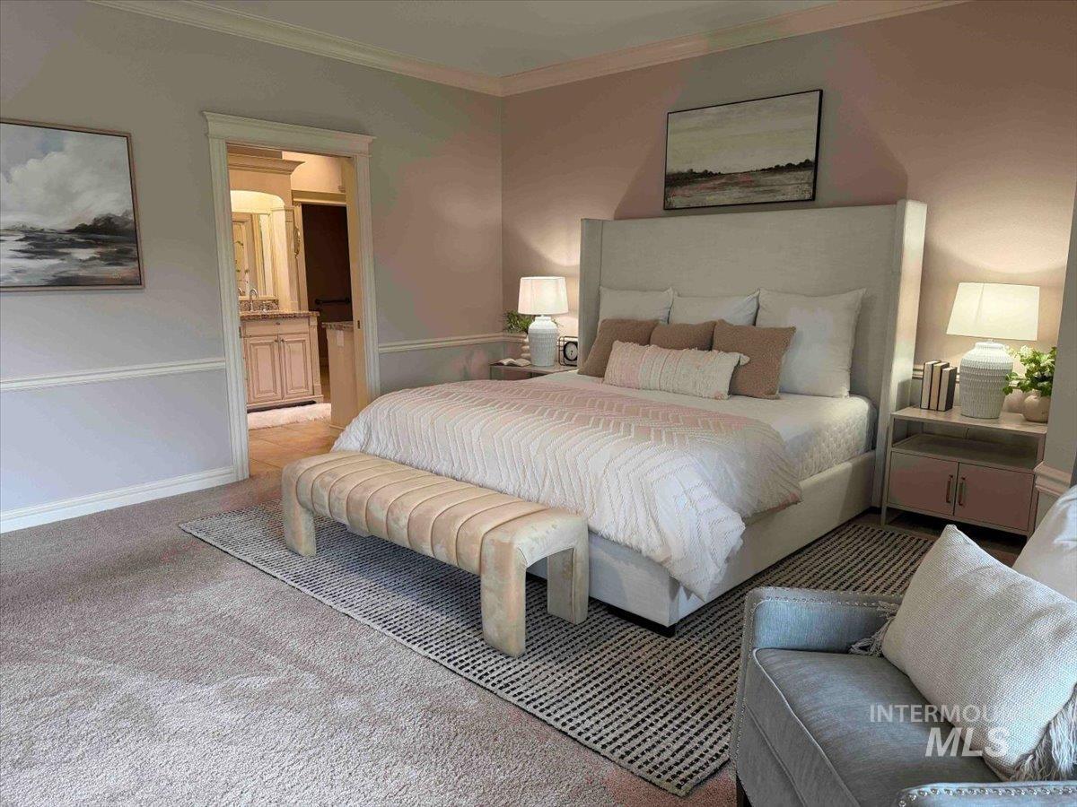 Carpeted bedroom featuring ensuite bathroom and ornamental molding