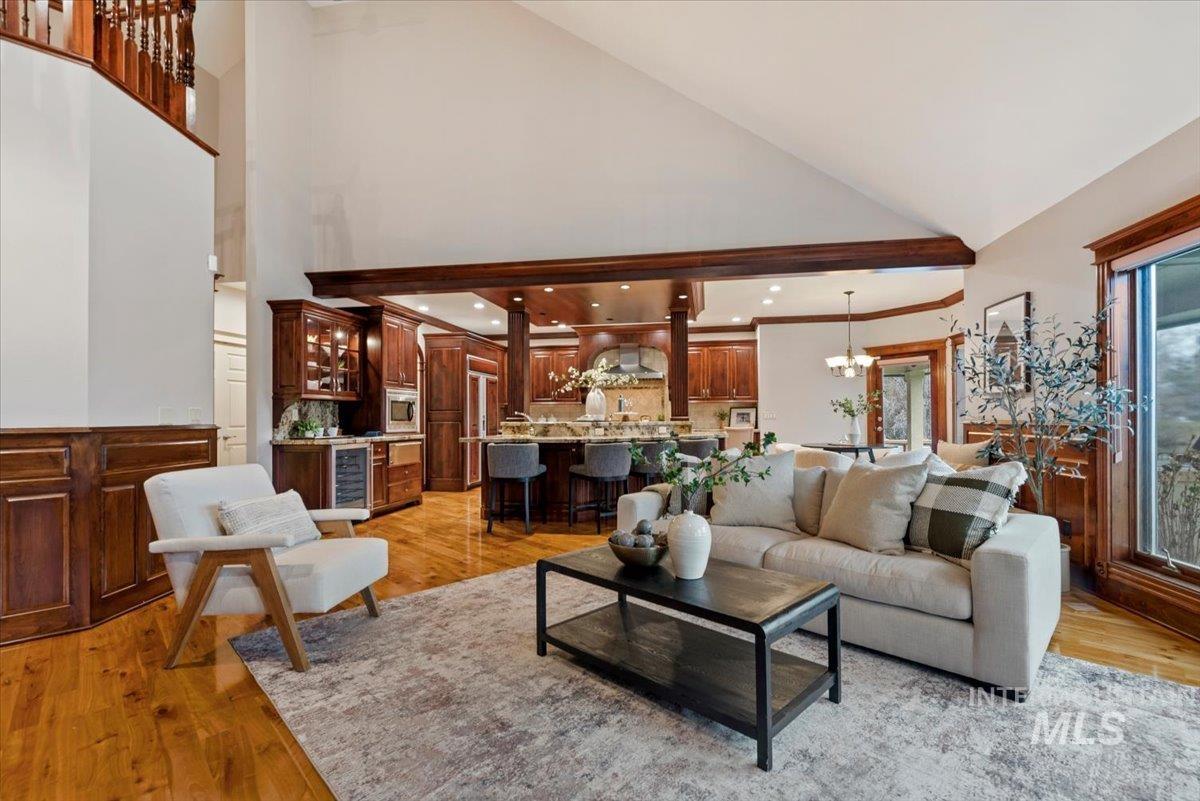Living area with light wood-style floors, wine cooler, lofted ceiling, and suspended lighting