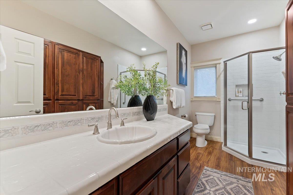 Full bath with vanity, a shower stall, and dark wood-style flooring