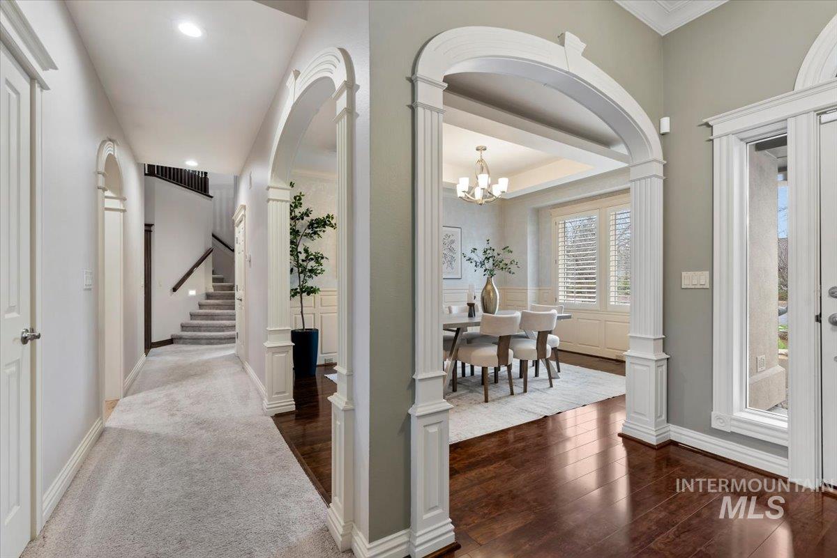 Entryway with a chandelier, ornate columns, dark wood finished floors, and arched walkways