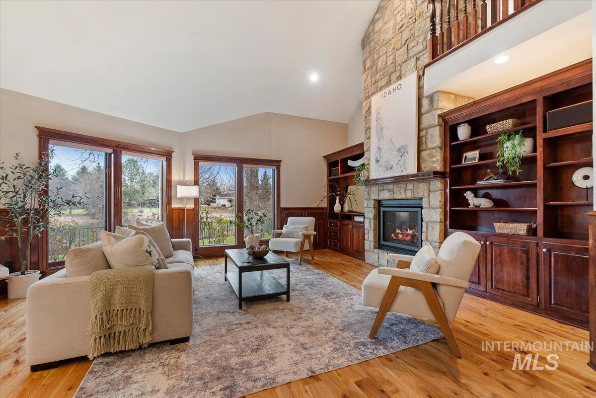Living room featuring vaulted ceiling, a wainscoted wall, light wood-style flooring, a fireplace, and recessed lighting